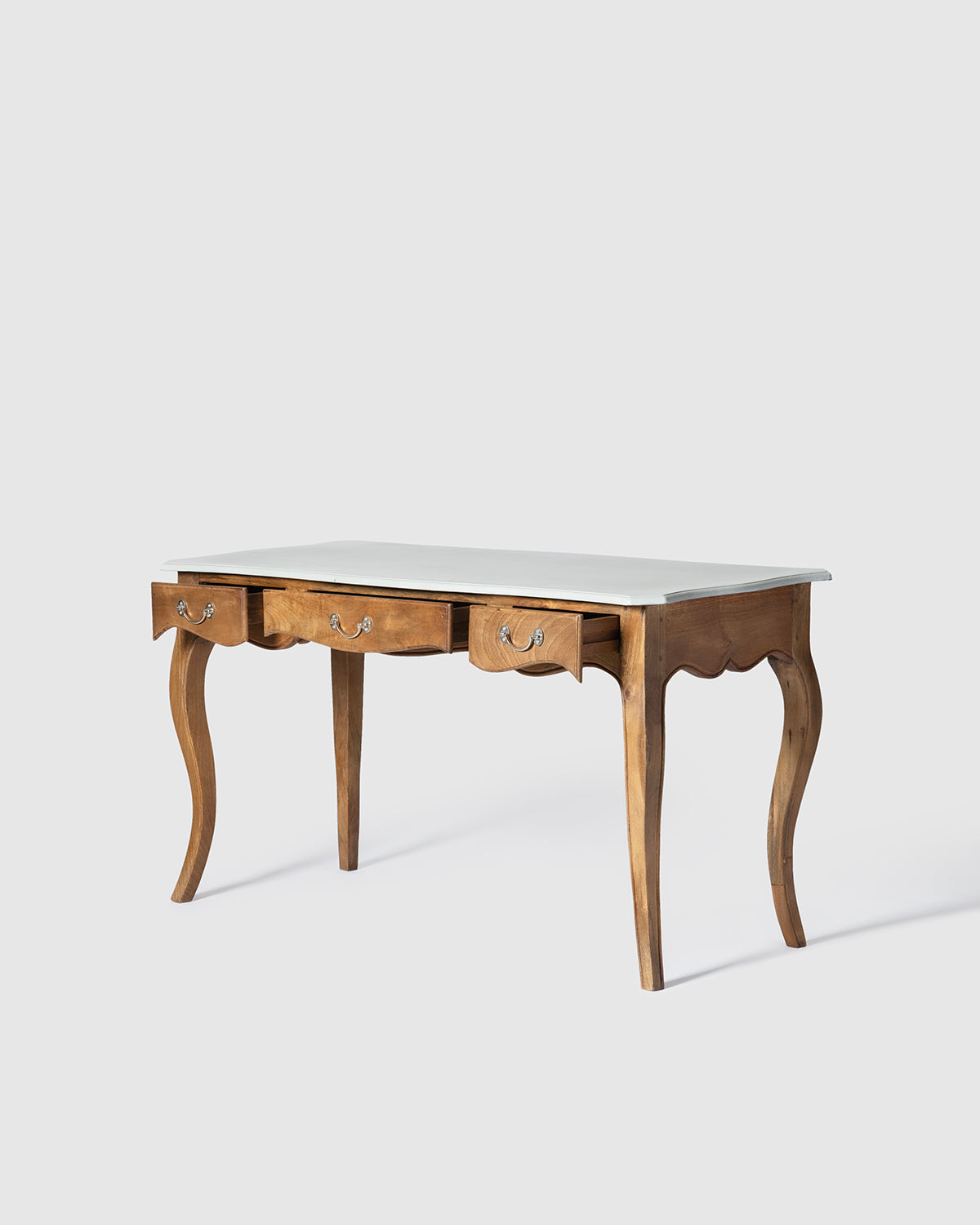 A wooden writing desk with curved cabriole-style legs, three front drawers with ornate metal pulls, and a light gray wooden top