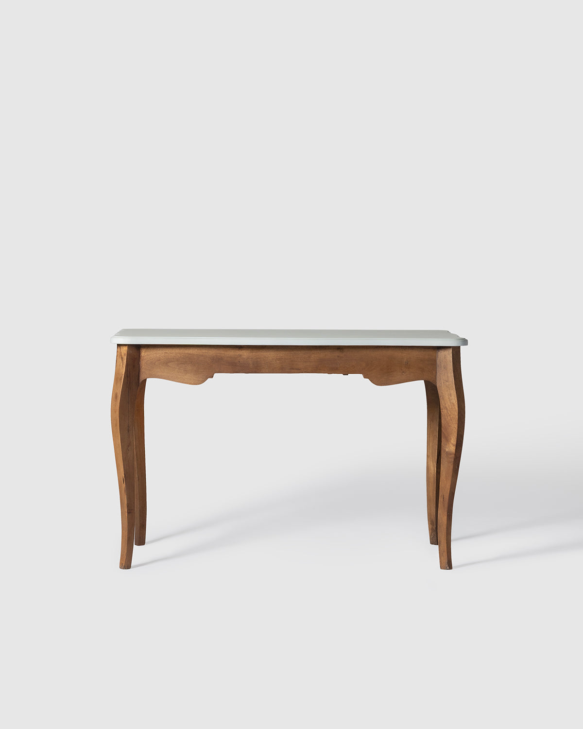 A wooden writing desk with a light gray top and curved legs in colonial finish