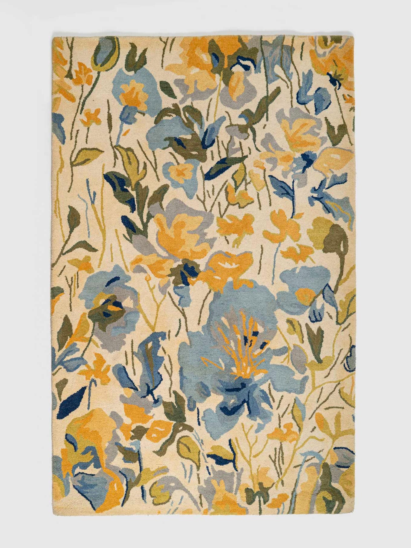 A rectangular wool rug with a vibrant floral pattern featuring multiple colors such as blue, yellow, and green, on a beige background.