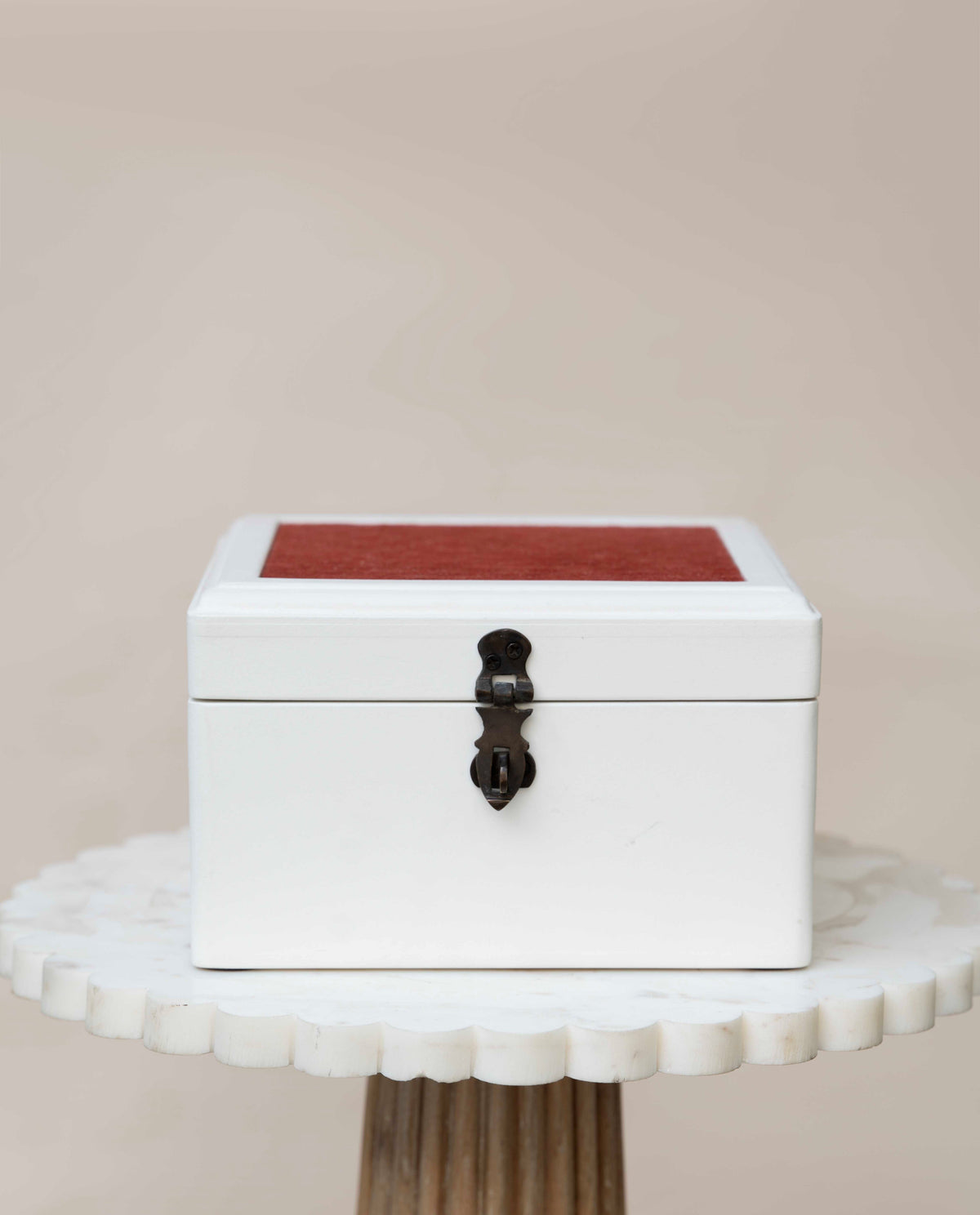 A wooden white jewelry box with a red cloth on lid and a black metal clasp