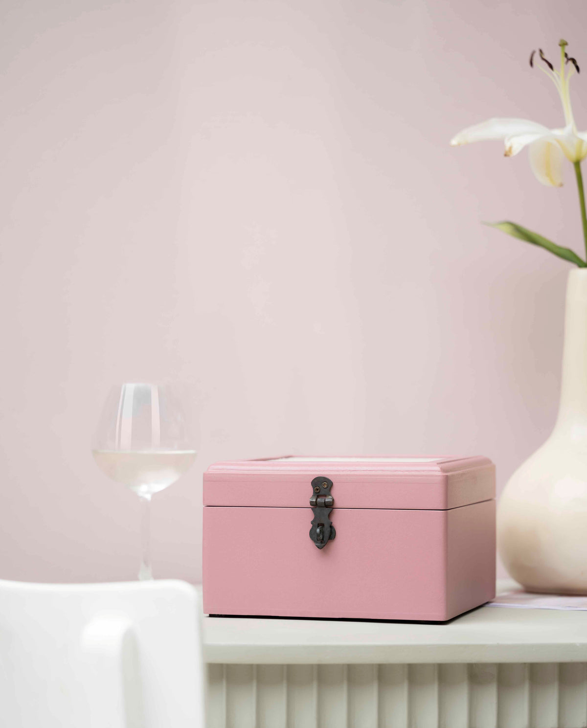 A pink painted wooden storage box with a black metal latch
