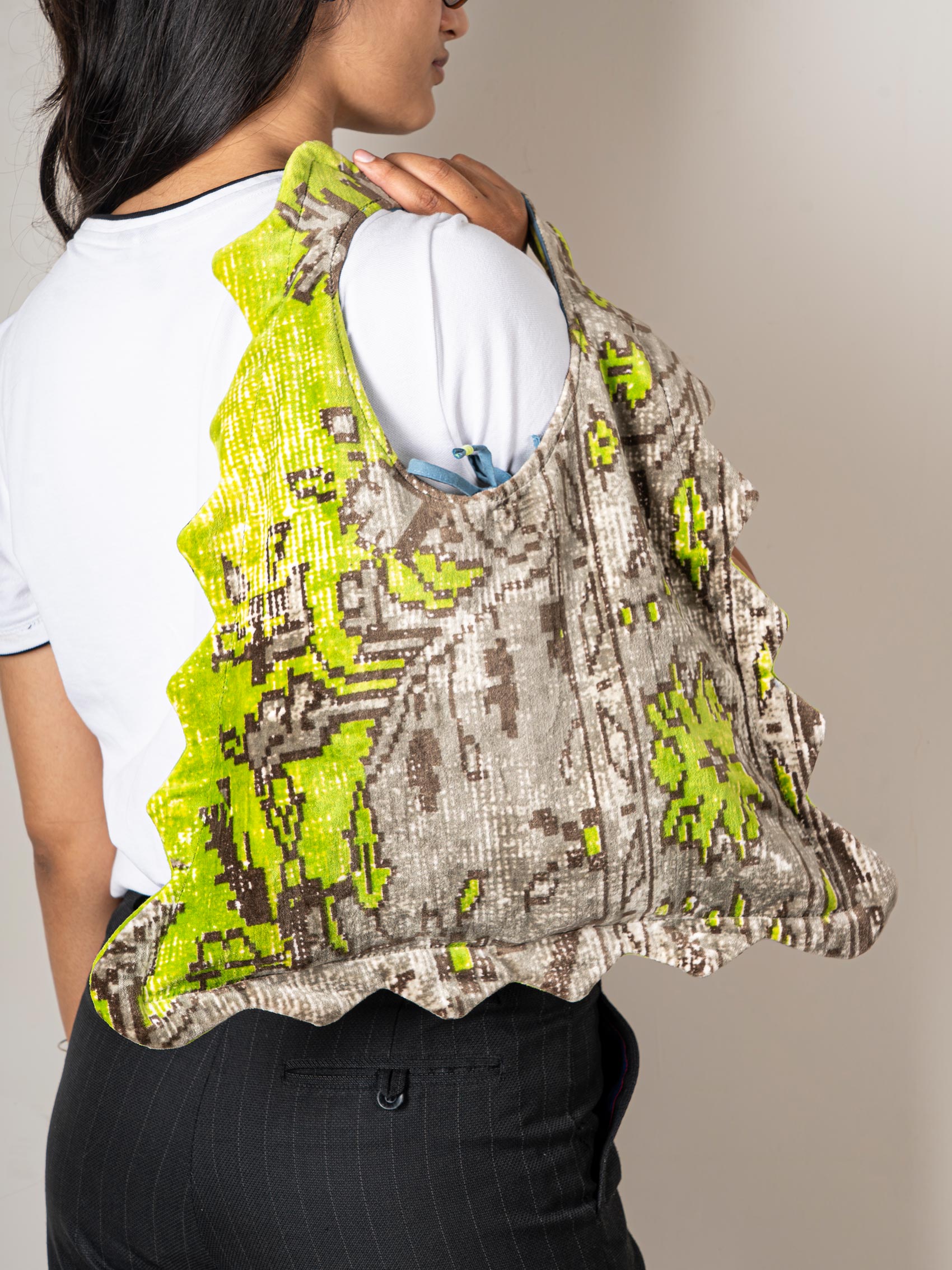 A green and gray printed tote bag over a woman's shoulder