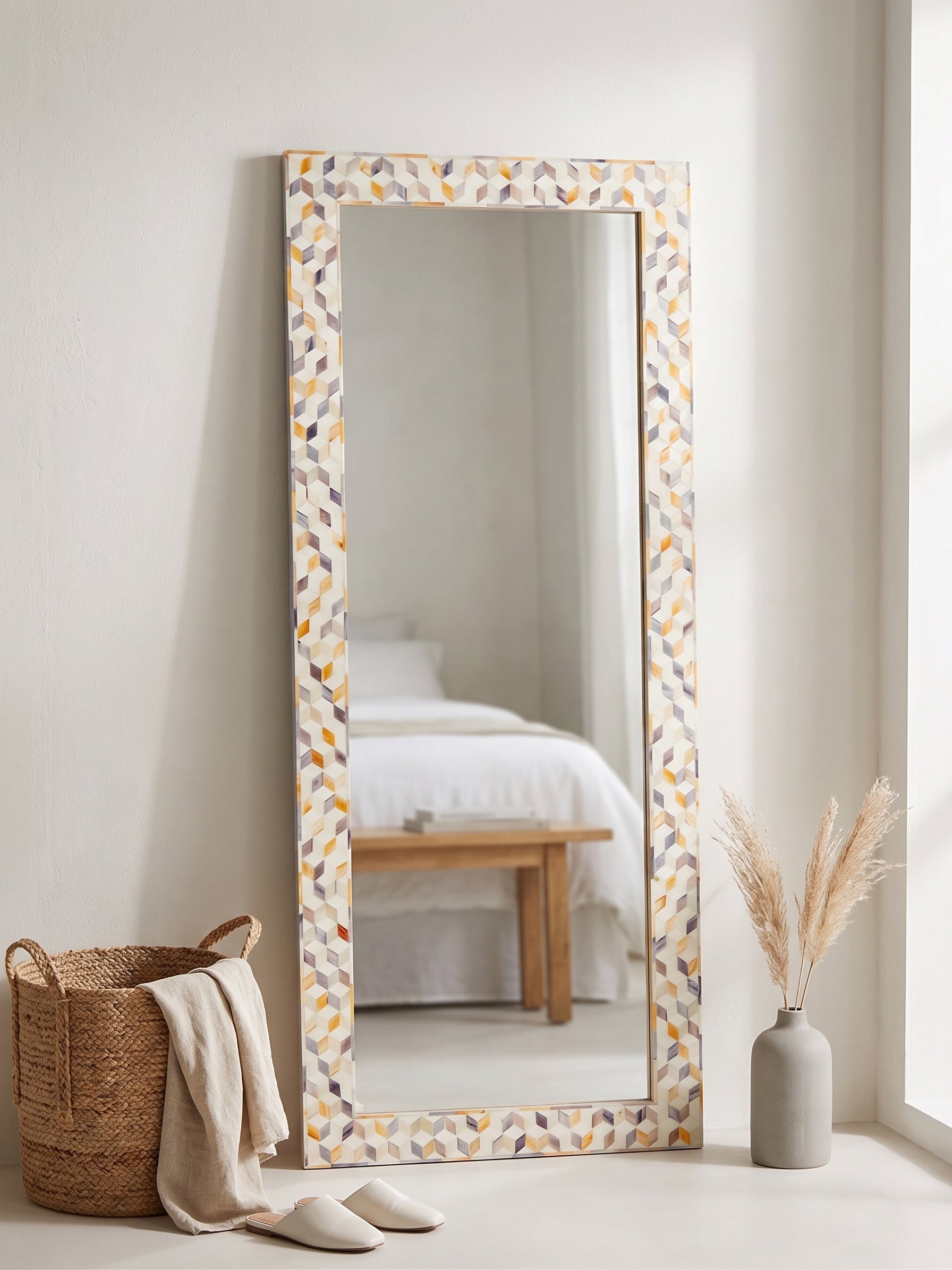 Decorative full-length mirror with a patterned frame made of dyed bone leaning against a wall.
