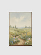 Framed painting of a landscape with a path and flowers on a white wall