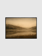 Framed photograph of a misty landscape with hills and a lake on a light gray background