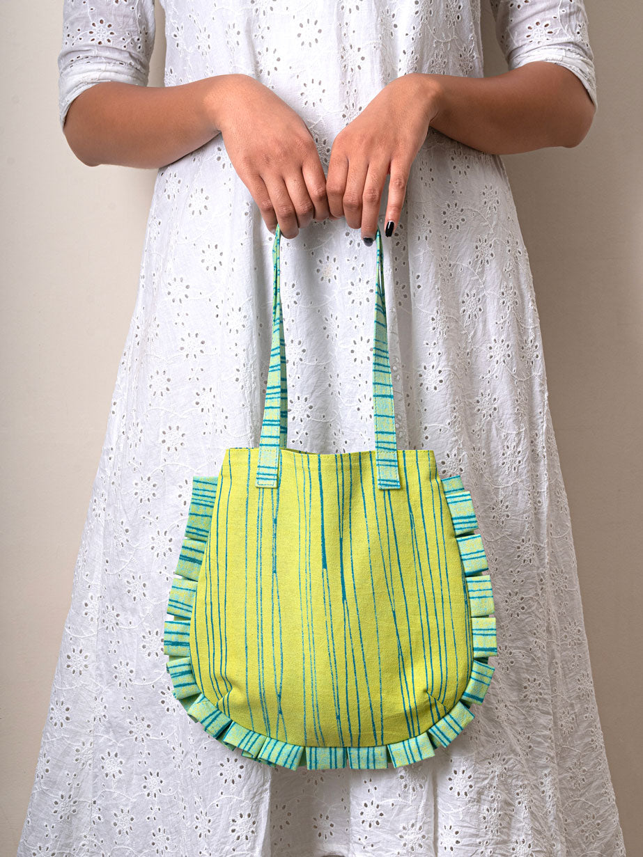 Person holding a green and blue striped handbag