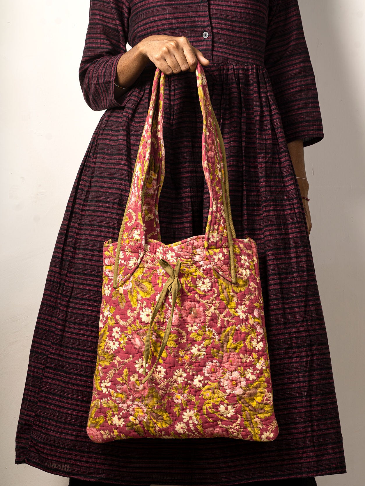 Girl holding a floral-patterned tote bag against a plain background
