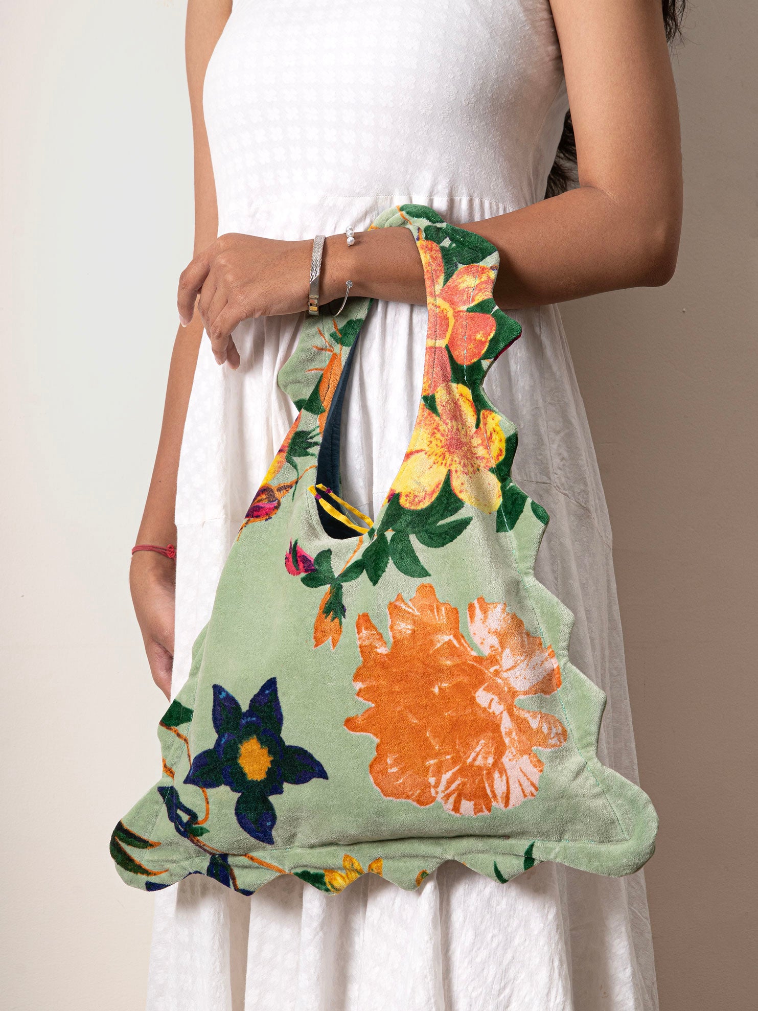 Floral-patterned bag held by a person wearing a white dress
