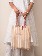 Woman holding a striped tote bag with 'Good Day, Ahead' text